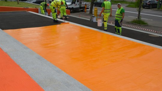 A început aplicarea stratului colorat pe pietonalul din Răcădău